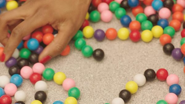 Close up of a light skinned hand grabbing colorful circular beads