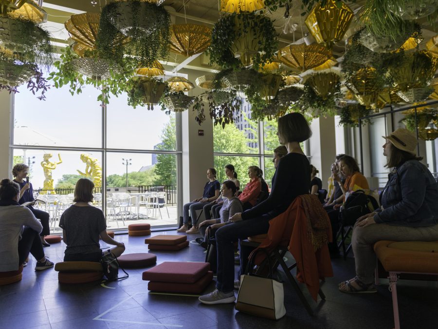 A group of people sit in meditation beneath the ceiling planters of the Commons.