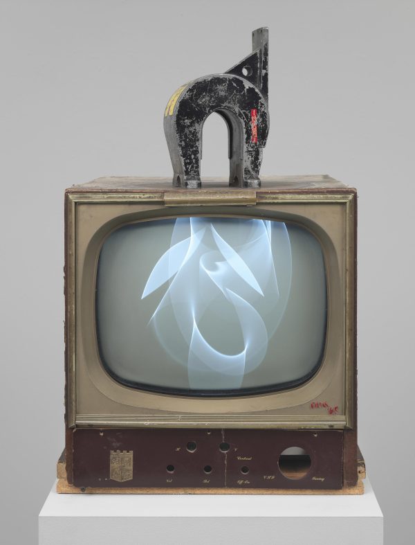 An old tv displaying a white wave-like form on a white pedestal with a magnet on top