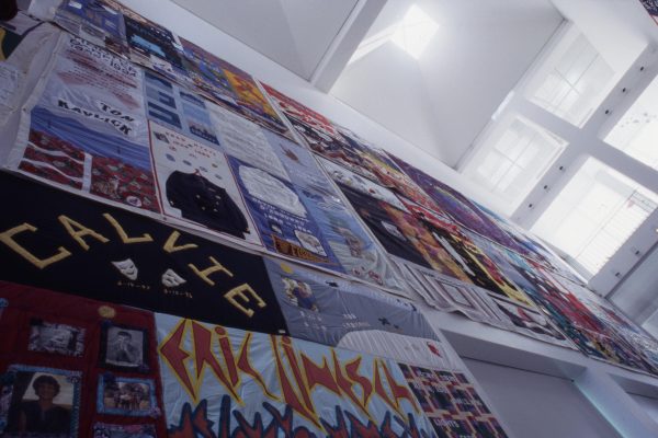 Large fabric panels with text and images cover a wall in a two-story room
