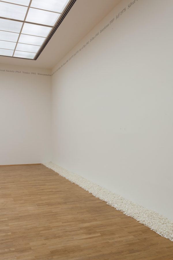 A seemingly empty gallery space until you notice a pile of white candy lining one wall.
