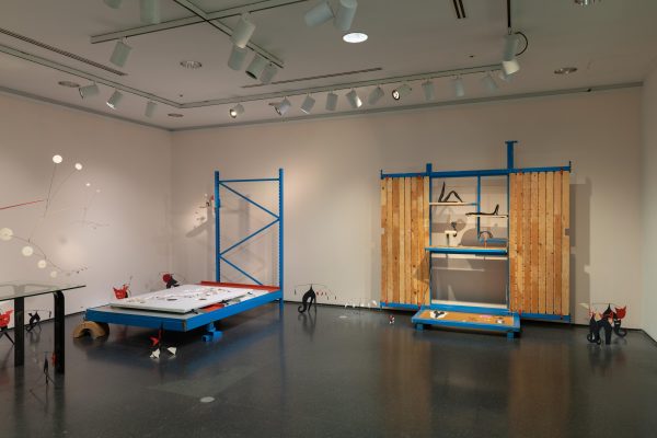 Gallery installation featured blue storage shelves and moving equipment