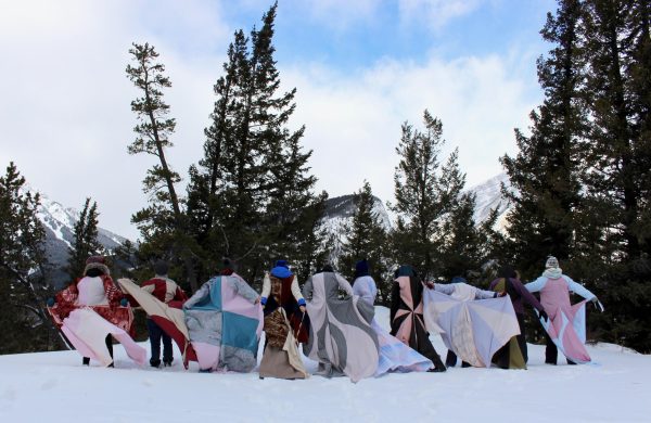 A group of people with quilts out in a snow-covered landscape.