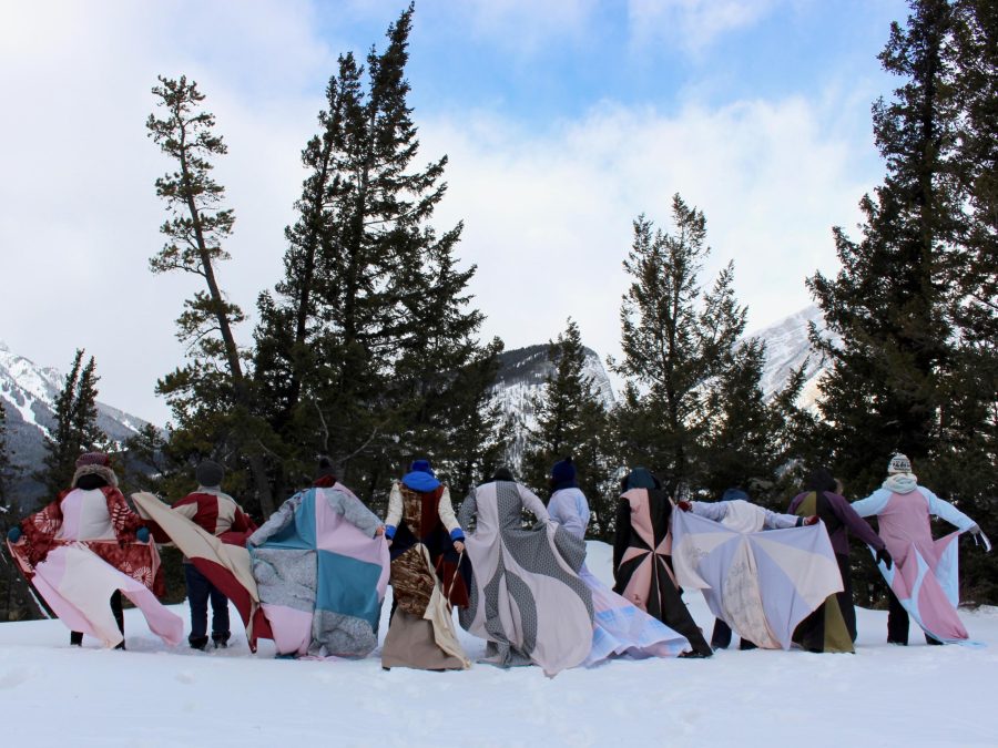 A group of people with quilts out in a snow-covered landscape.