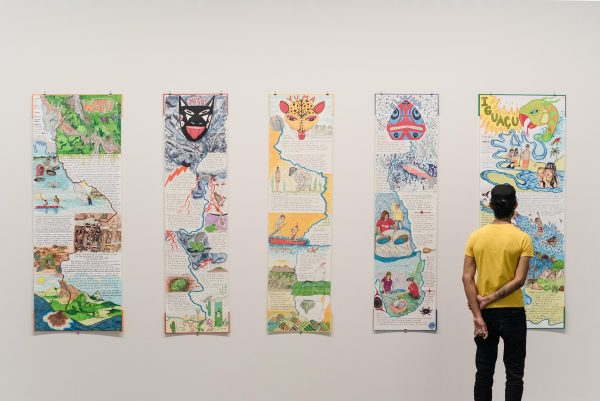 A person looks at the fifth column in a wall displaying five columns of drawings