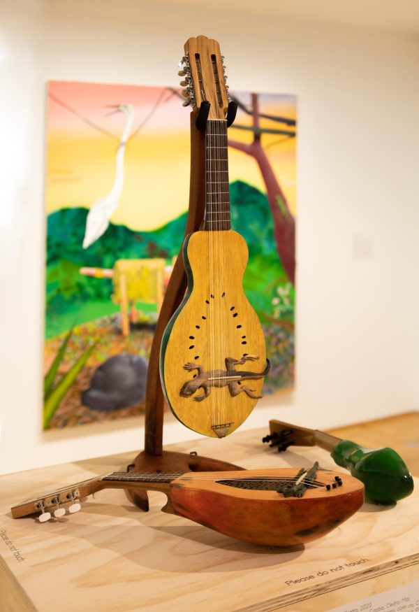 Handmade string instruments on a table in front of a painting on a white wall