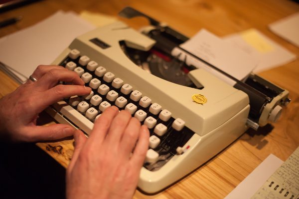 Disembodied hands hover over a vintage typewriter