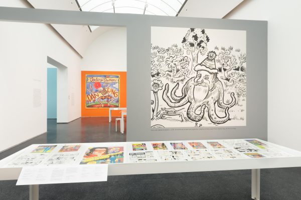 Exhibition interior showing a large line drawing of a Santa Claus octopus on a gray wall.