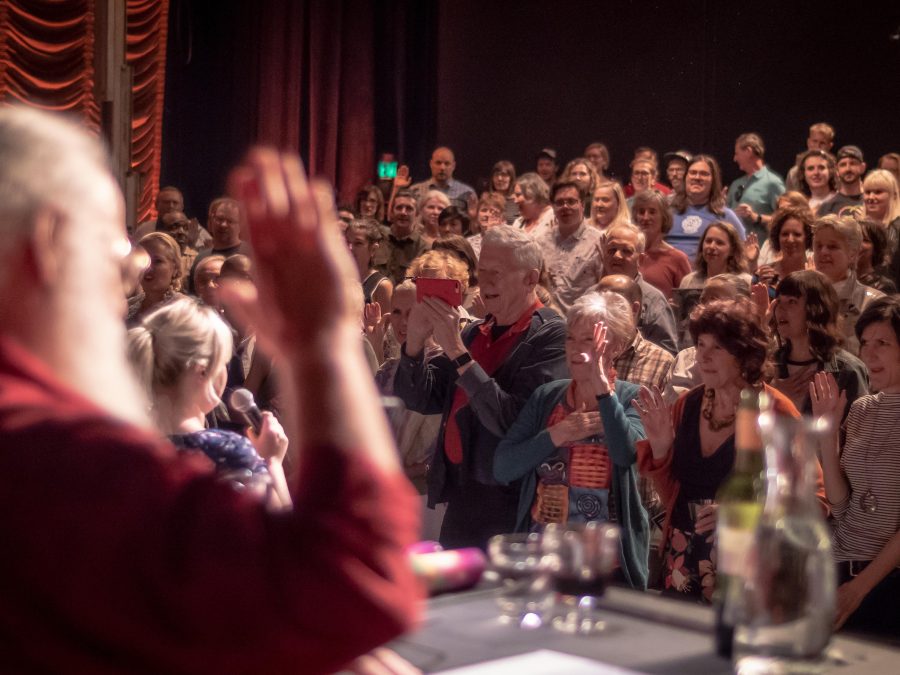 An audience raises their right hand while they watch a performance