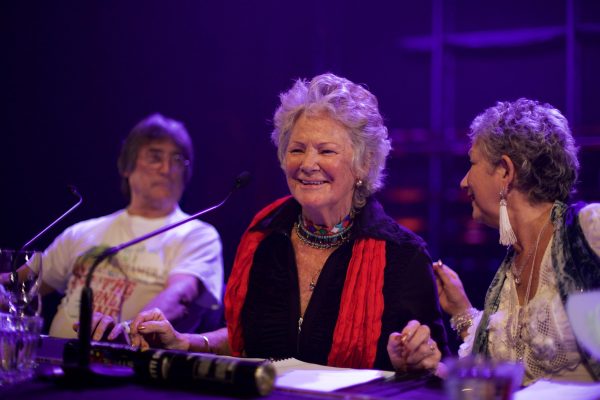A woman smiles leaning toward a microphone