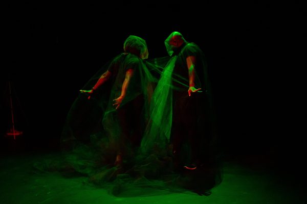 Two people covered in gauze make expressive body gestures with their arms outstretched