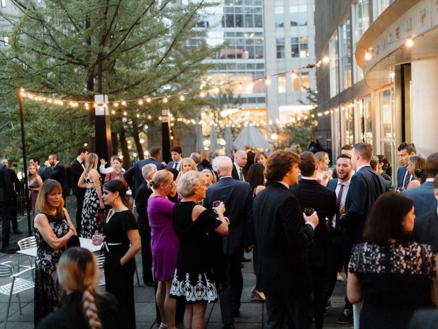 A crowd in business attire gathered for an outdoor event under string lights