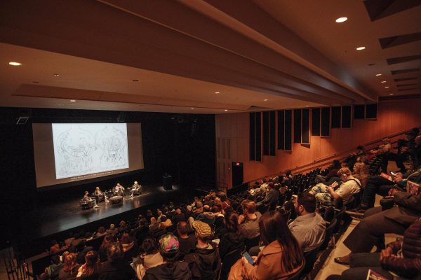 audience seated while listening to speakers on stage