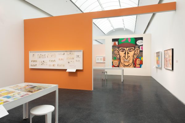 A view of three rooms seen through two doorways. The walls are covered in art.