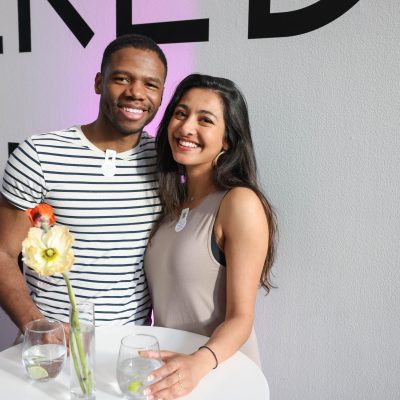 Two people pose for the camera while standing at a cocktail table.